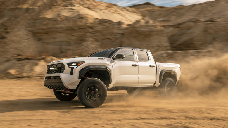 2026 Toyota Tacoma TRD Pro cornering at speed on dirt road front 3/4 view