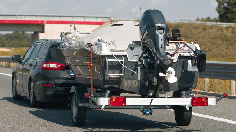 A black Ford Mondeo wagon towing a small boat.