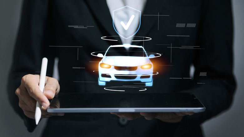 A holographic vehicle hovers above a tablet held by a man in a business suit, while lines and curves illustrate potential data.