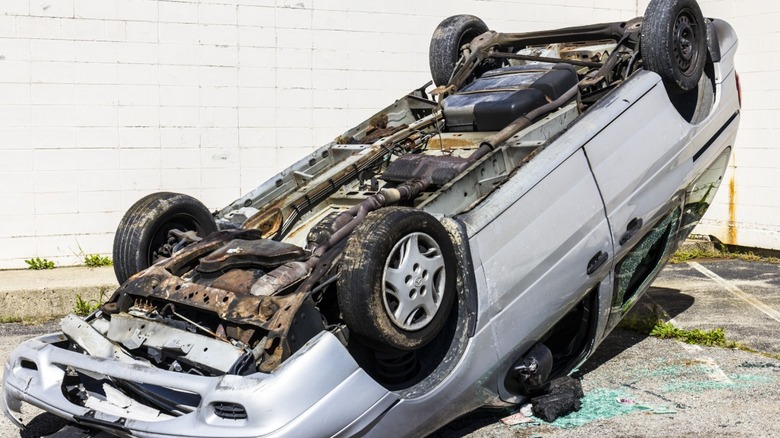 A wrecked gray sedan, upside down