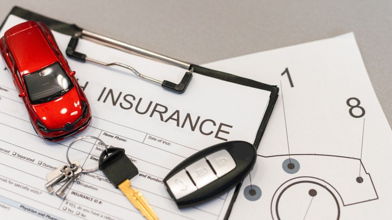 Car keys and a toy car on top of insurance paperwork