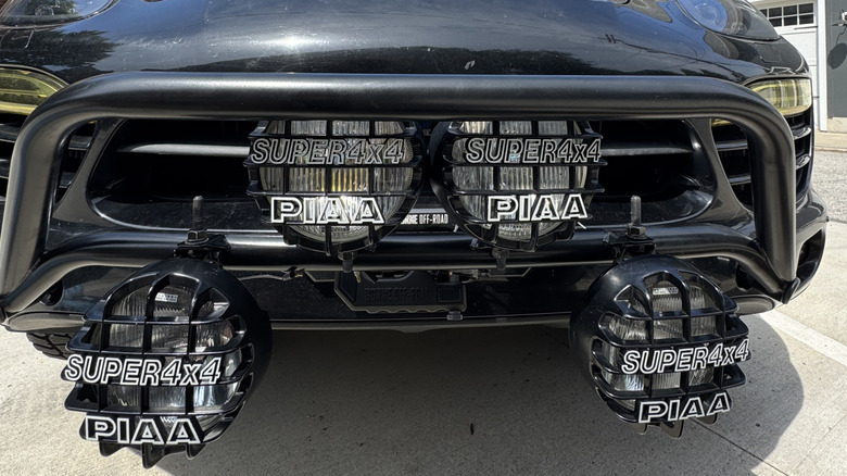 Four off-road lights mounted to the front bumper of a Porsche Cayenne