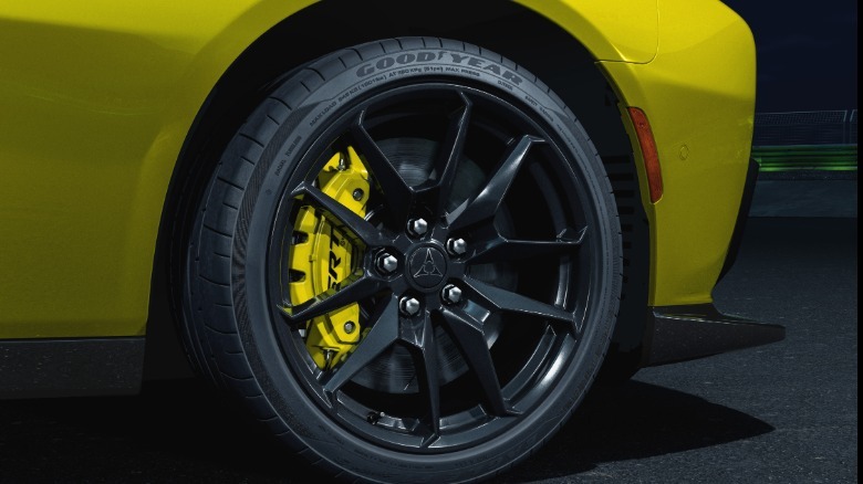 A close-up shot of the yellow Charger's front wheel showing the massive yellow brake caliper behind gloss black wheels