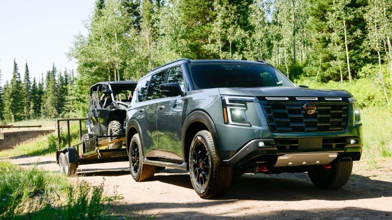 Front 3/4 view of a green Nissan Armada towing an ATV.