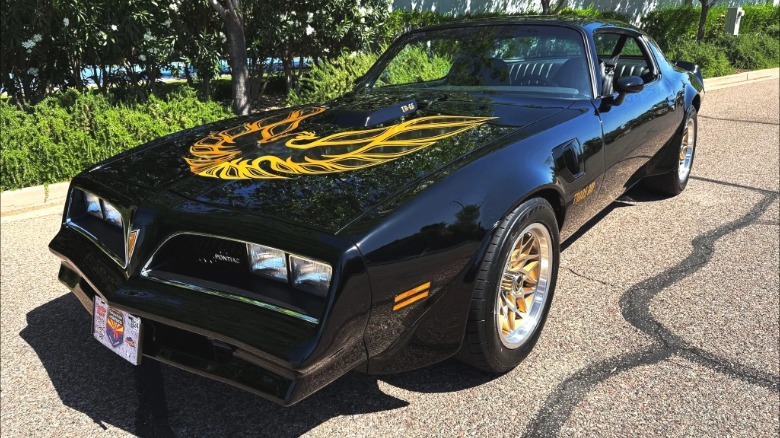 A front three-quarters shot of a black 1978 Pontiac Firebird with the gold screaming chicken on the hood