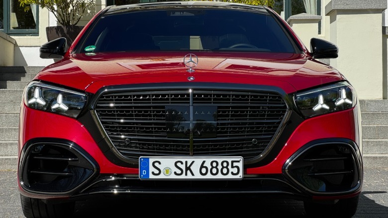 A head-on shot of the red S580 parked in front of concrete steps and a white building