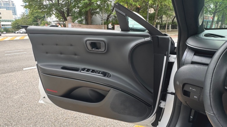 A photo of the inside of the driver's door while its open showing the riveted upholstery and frameless windows