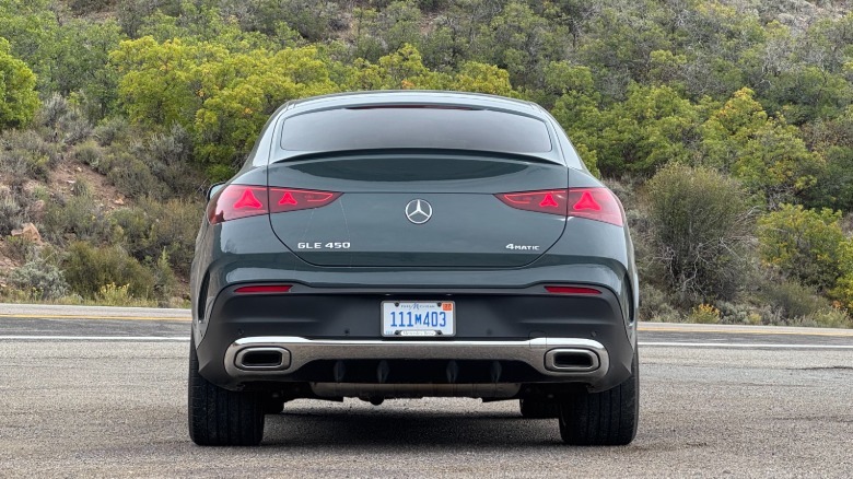 A shot of the rear of the gray GLE450 Coupe parked on gravel in front of a view of trees