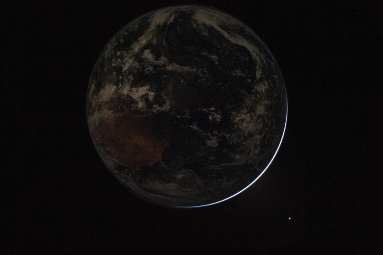 A view of a backlit Earth taken by NASA astronaut and Artemis II Commander Reid Wiseman from one of the Orion spacecraft's window after completing the translunar injection burn on April 2
