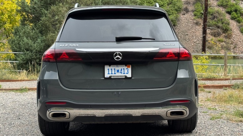 A rear shot of the gray GLS580 parked on gravel in front of trees