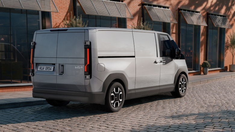 Rear three-quarters shot of a white cargo van parked on cobblestone in front of a brick building