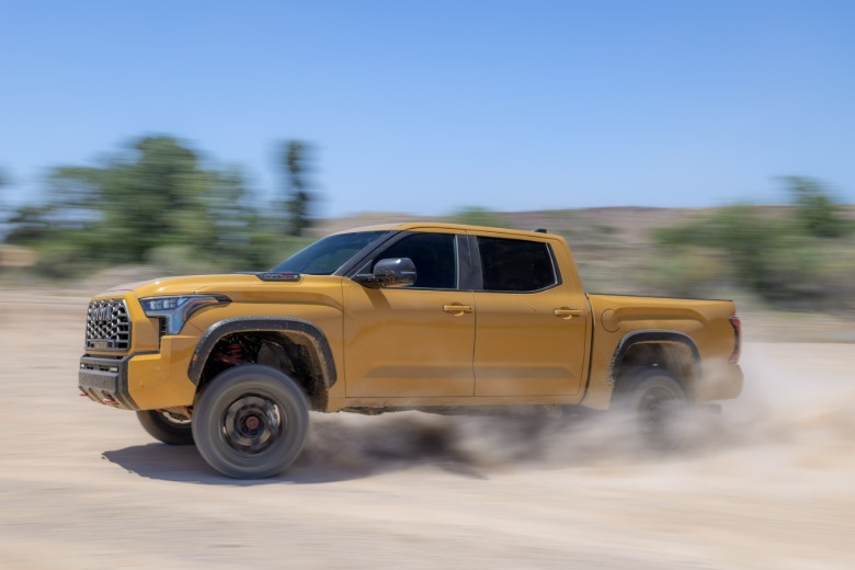 Side view of a yellow Toyota Tundra TRD Pro drifting on dirt