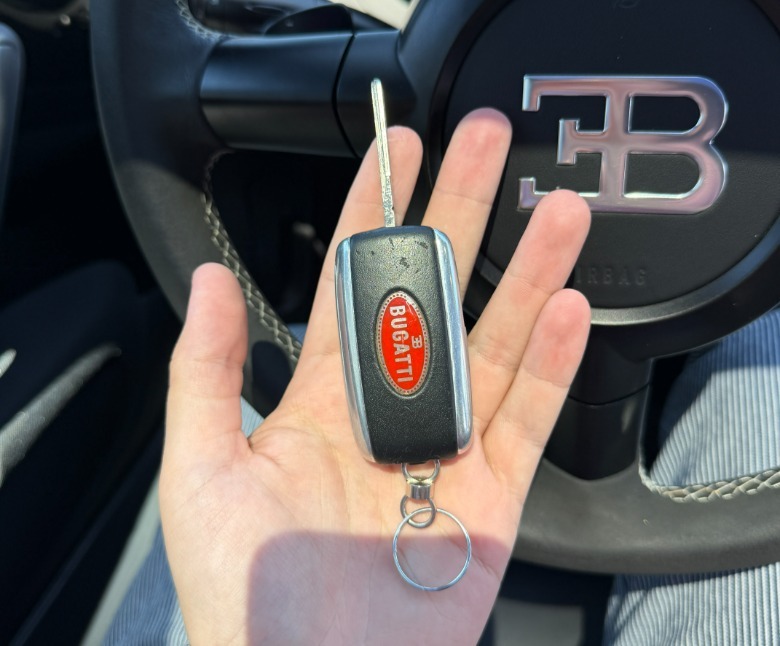 A hand holding a Bugatti Veyron key