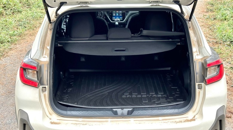 A look at the trunk of a dusty white Crosstrek Hybrid parked on gravel