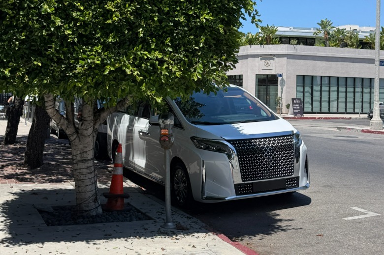 A white Faraday Future FX Super One hiding behind a tree