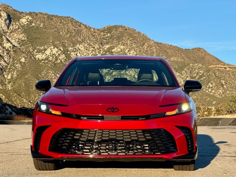 A head-on shot of the red Camry Nightshade parked in front of a blue sky and a mountain
