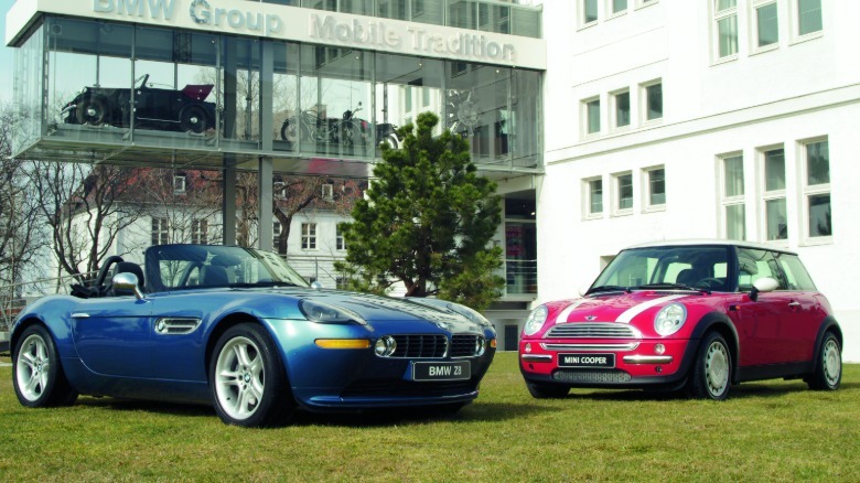 Front three-quarters shot of a blue BMW Z8 parked with its top down with a red-and-white first-gen Mini Cooper opposing it