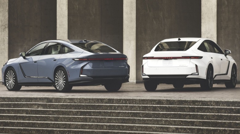 A photo of the rear of a gray-blue ES and a white one parked at the top of a staircase in front of concrete pillars