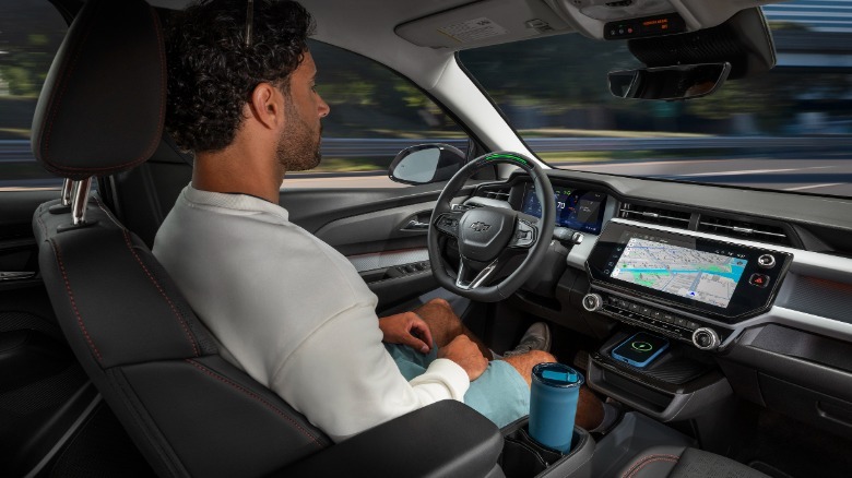 A photo from the back seat of a 2027 Bolt showing a driver with his hands off the wheel letting Super Cruise drive