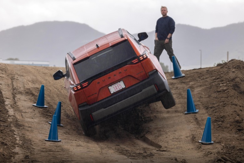 An orange Subaru Uncharted driving up a dirt hill