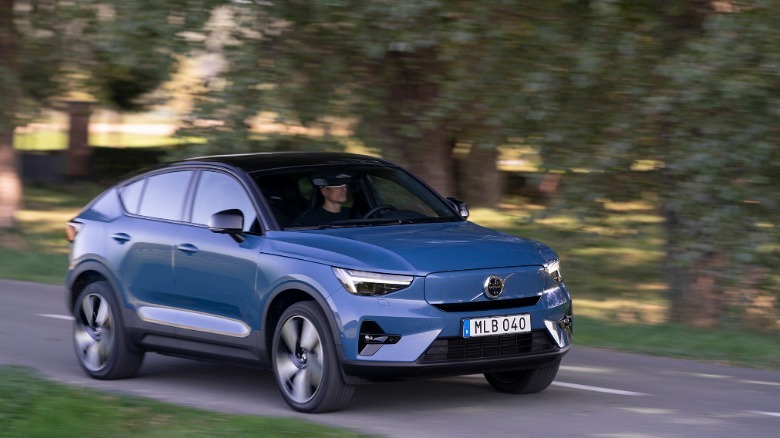 Front three quarters shot of a blue C40 driving on a road past trees and grass