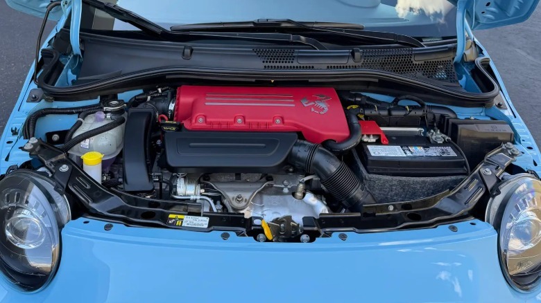 A look under the hood of the light blue Fiat showing the bright red engine cover