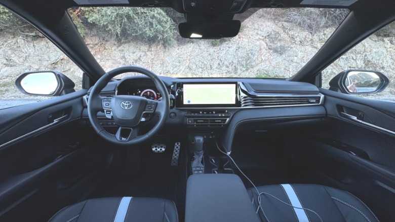 A wide shot of the dashboard showing its all-black color scheme and a mountainside out the windshield