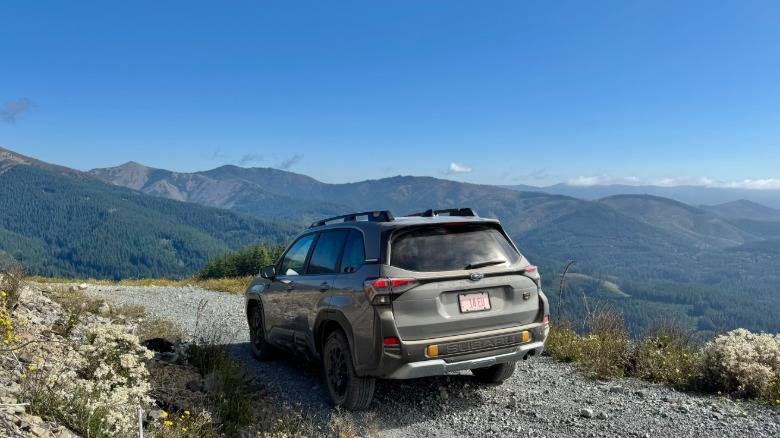 A rear three-quarters shot of a gray Forester Wilderness parked on a rocky trail in front of a spanning mountain view