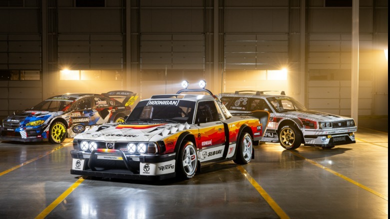 A photo of the Brataroo parked in front of the Family Huckster and a Hoonigan Subaru STI parked in a warehouse