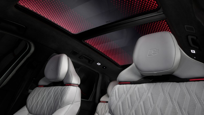 Photo looking up at the white front seats and the illuminated glass sunroof in an SQ9