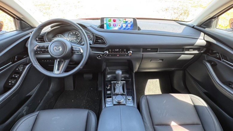 A wide shot of the dashboard and front seats the CX-30's black leather interior