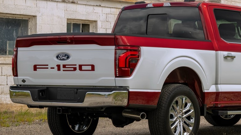 A rear three-quarters close-up of the bed of a red F-150 with the white stripe