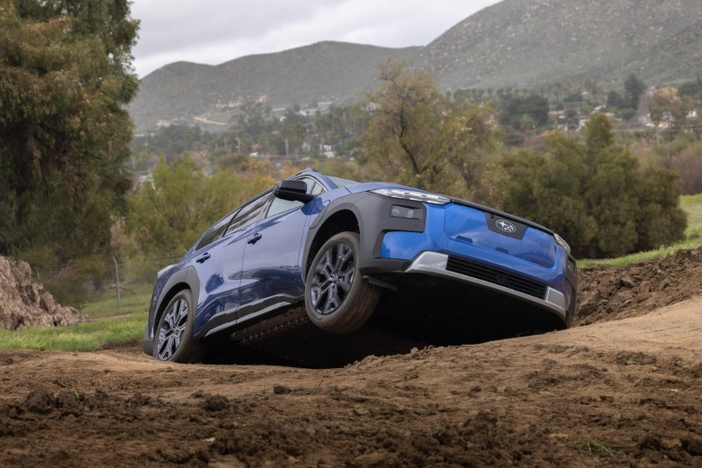 A blue Subaru Trailseeker coming over a muddy hill