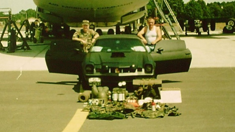 Helge Meyer and a soldier post with the Ghost Camaro and the supplies it will be delivering to war-torn Bosnia