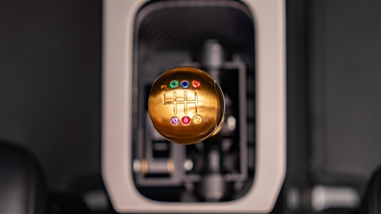 A close-up of the gold shift knob with six different colored gems denoting the shift pattern