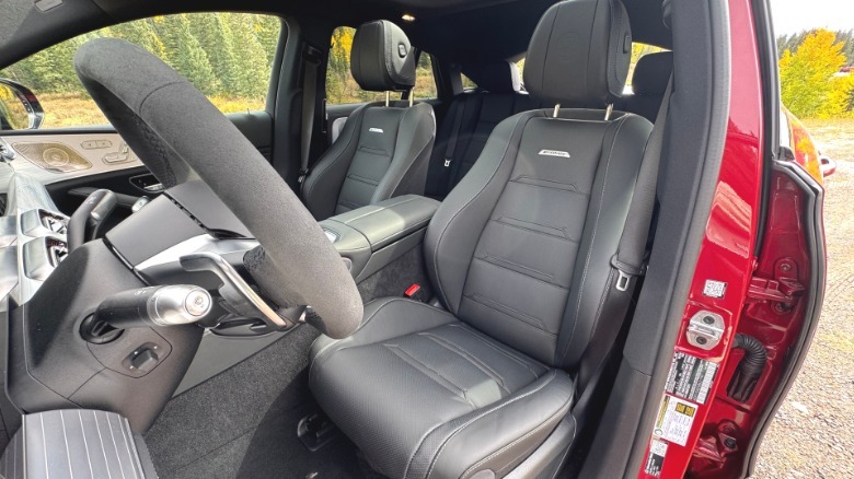 A shot looking through the open driver's door back at the black driver's seat in the red GLE53 Coupe with yellow trees in the background