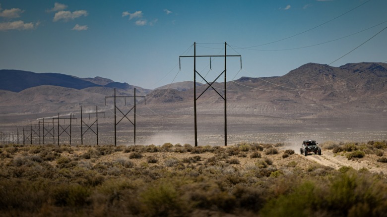 A 2026 Can-Am Maverick R MAX X RS with a line of transmission towers in the background