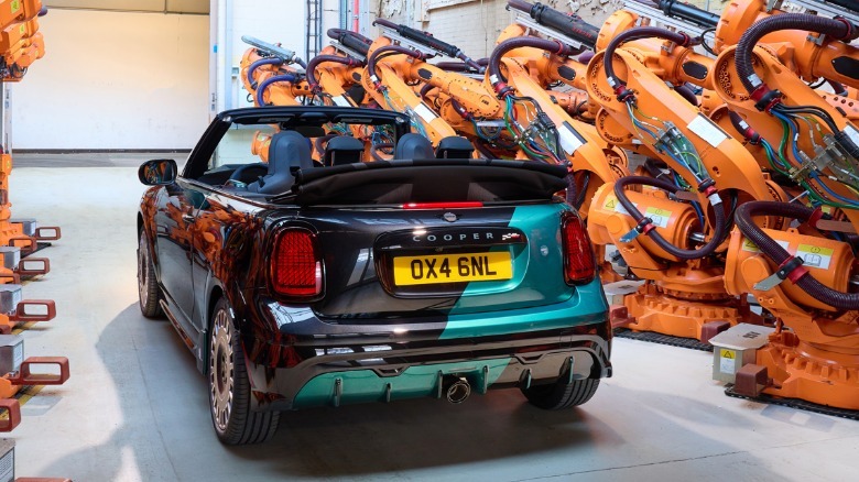 A rear three-quarters shot of the custom Mini in a room lined with orange car assembly robots