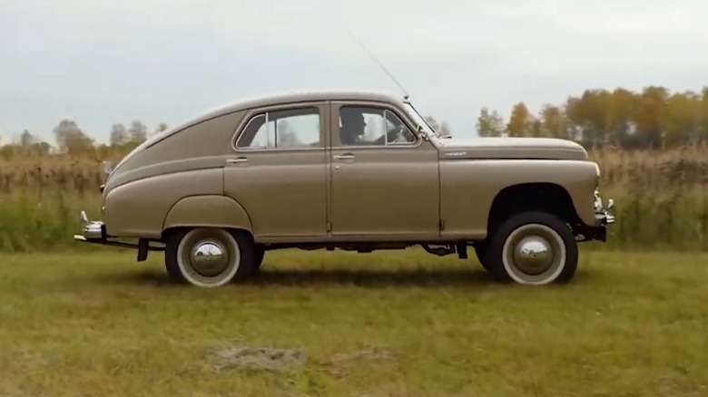 A side shot of the tan M-72 driving on grass in front of taller grass