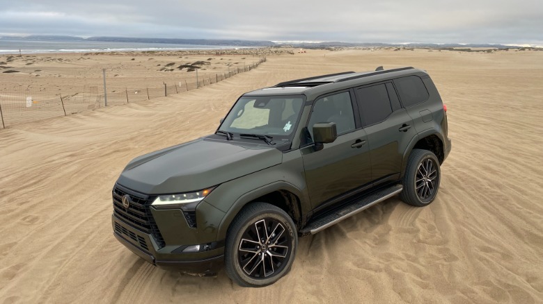 A front three-quarters shot of a dark green Lexus GX55- parked on the sand at Oceano Dunes SVRA on an overcast day