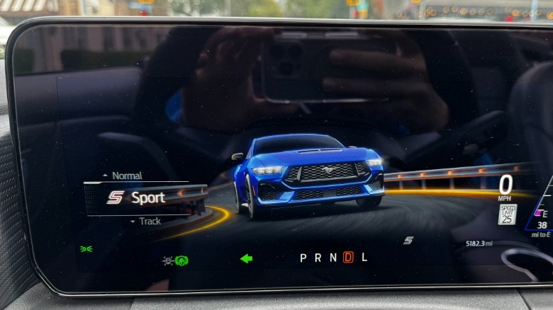 A close-up of the Mustang's digital gauges showing a blue Mustang driving at the screen in Sport mode
