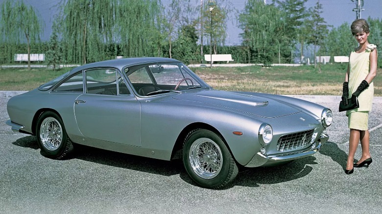 A woman posing next to a silver Ferrari 250 Lusso