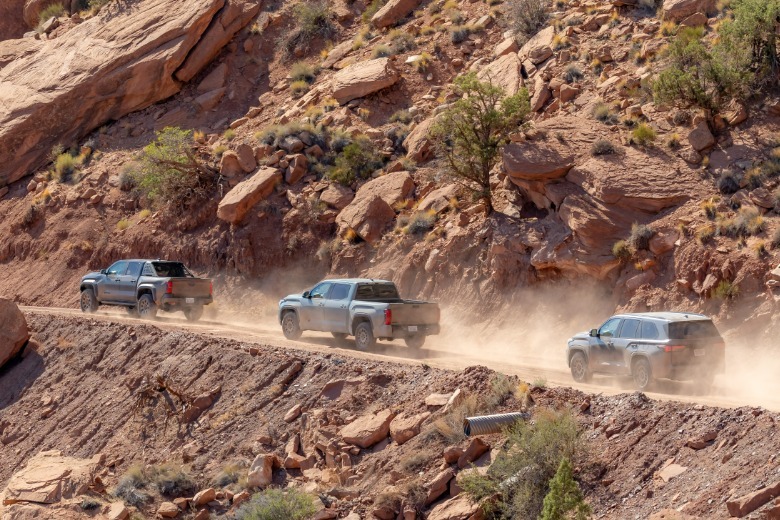 Three Toyota trucks driving on a trail