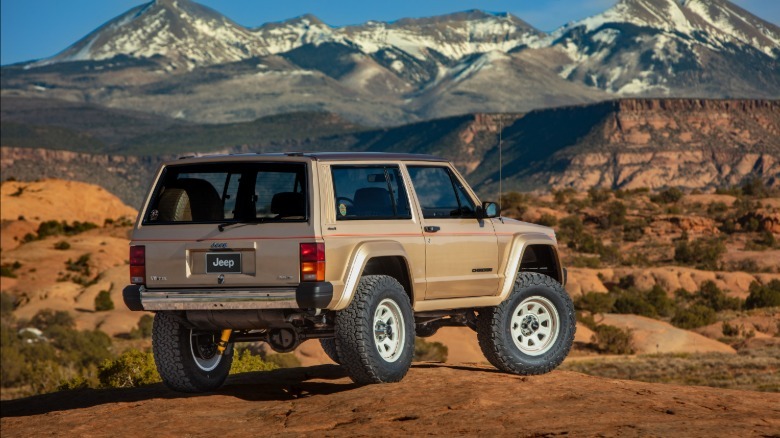 Rear 3/4 view of the 1986 Jeep Cherokee restomod that Jeep calls the XJ Pioneer with snowy mountains in the background