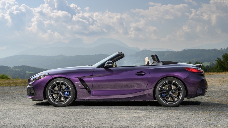 A purple BMW Z4 G29 parked outside against a cloudy sky with mountains.