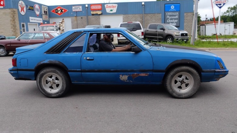 Side view of a blue 1979 Ford Mustang with lots of rust and body damage
