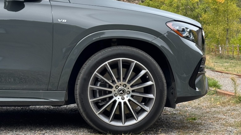 A photo of the front quarter panel of the gray GLE580 and its V8 badge with trees behind it