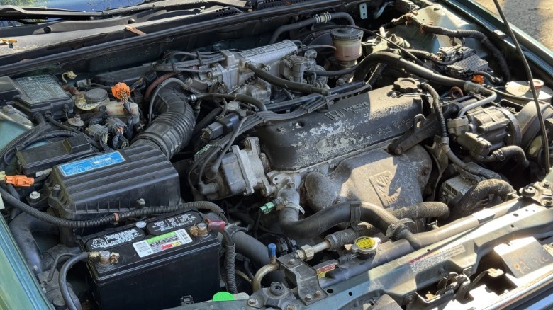 A photo under the million-mile Accord's hood showing the 2.2 liter four cylinder engine with some corrosion on the valve cover