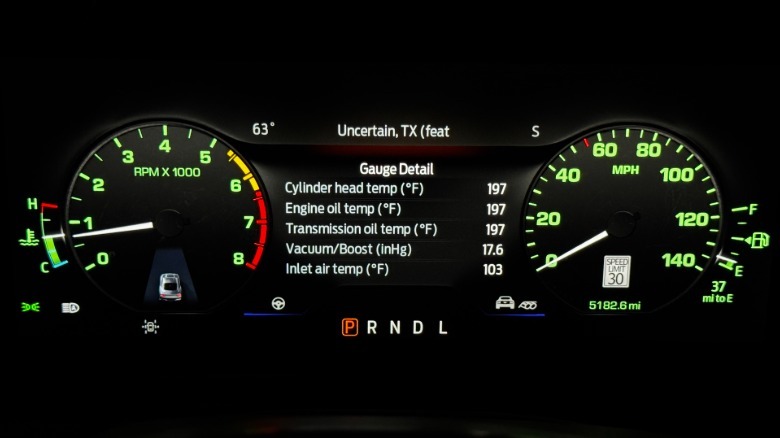 A close-up of the Mustang EcoBoost's Fox Body-style gauge cluster at night with the numbers glowing green