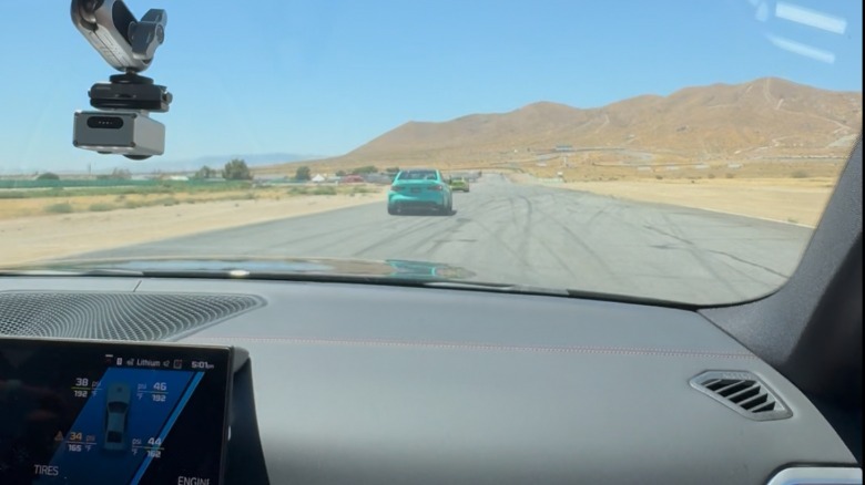 A photo of the passenger's POV in the M3 as it enters the straightaway following a turquoise M3